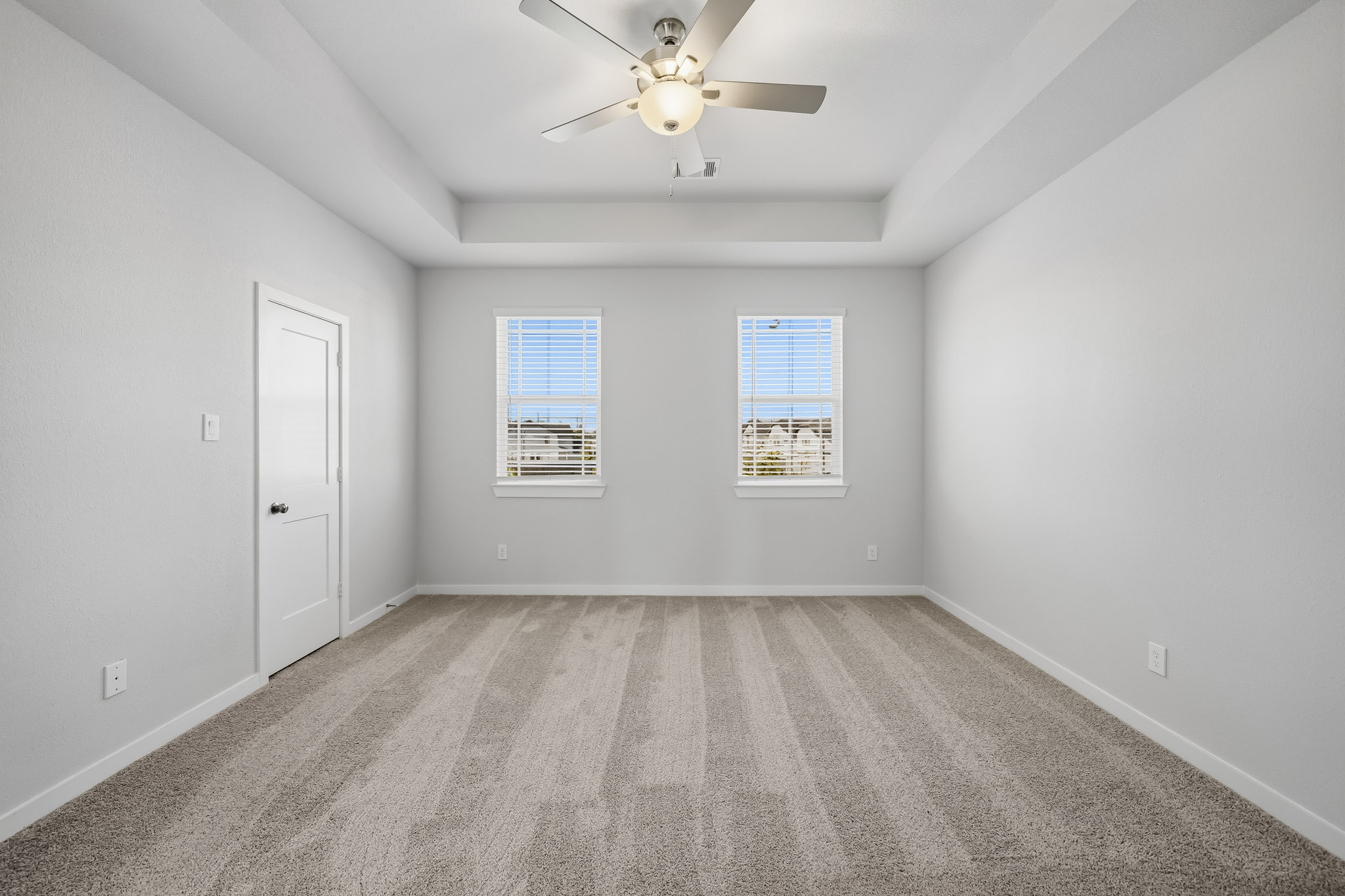 A room with a ceiling fan and a door.