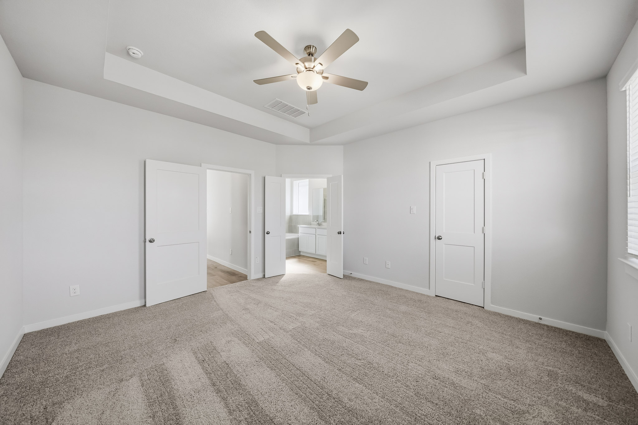 A room with white walls and a ceiling fan.