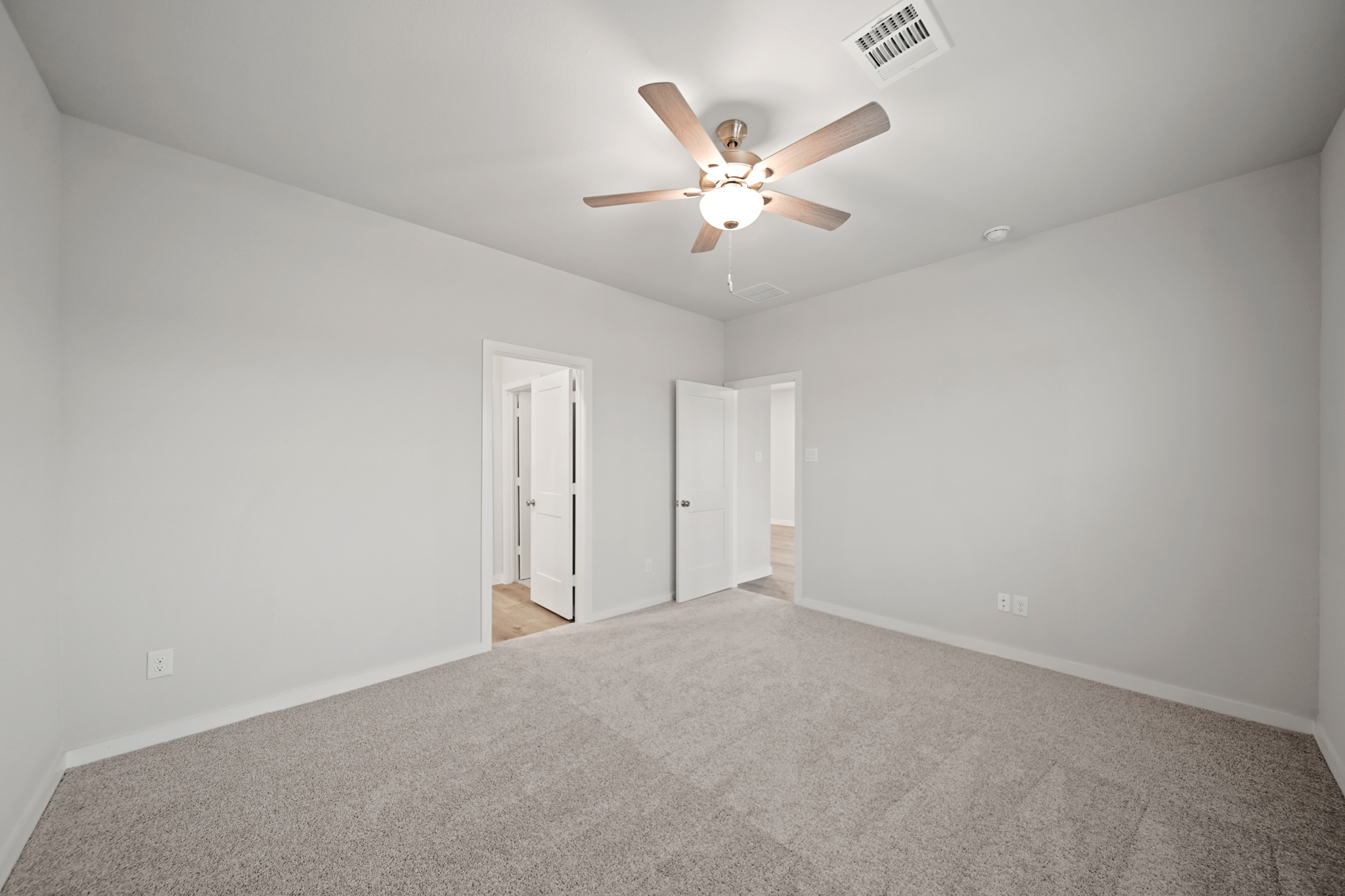 A room with a ceiling fan and a carpet.