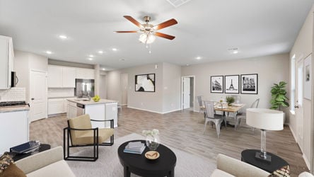 A large living room with a ceiling fan and a table.