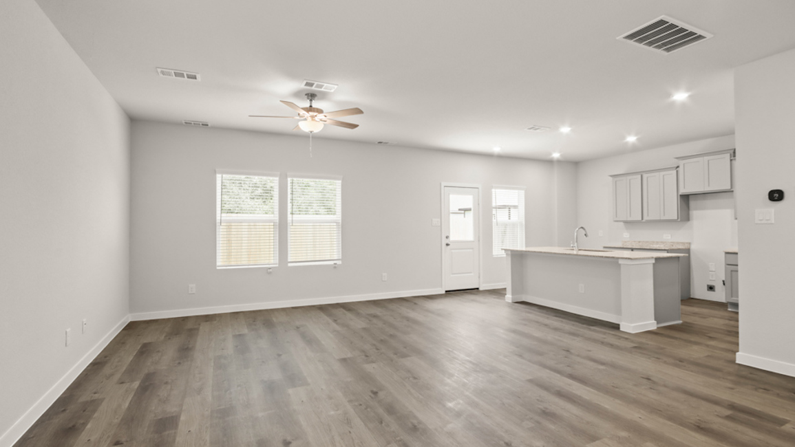 A large empty room with a wood floor and a ceiling fan.