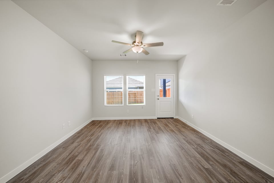 A room with a ceiling fan and a wood floor.