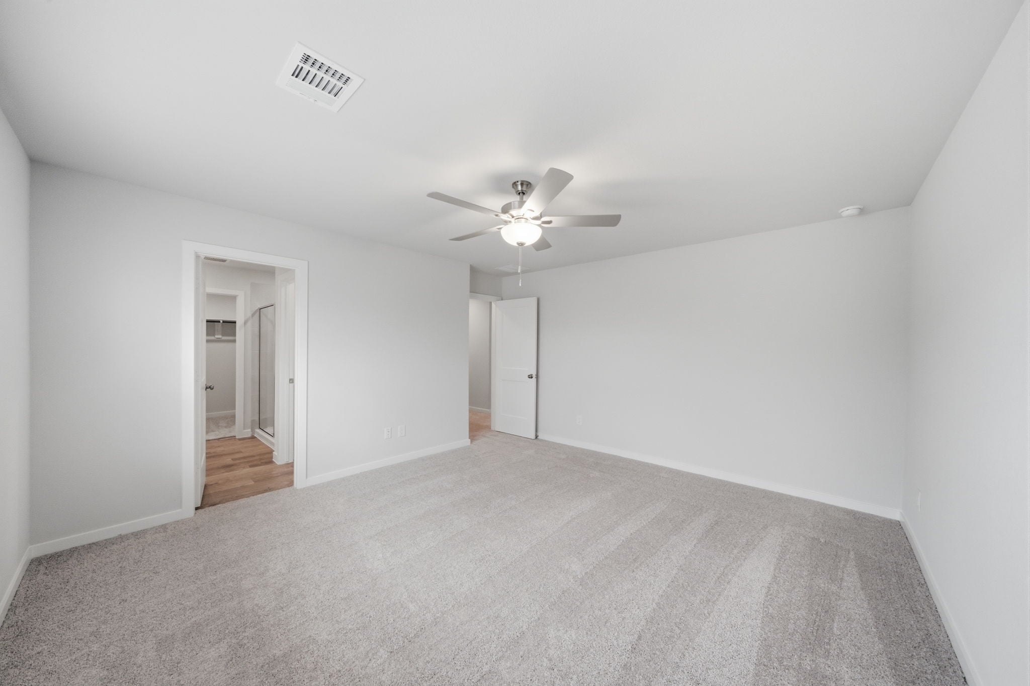 A room with a ceiling fan and a carpet.