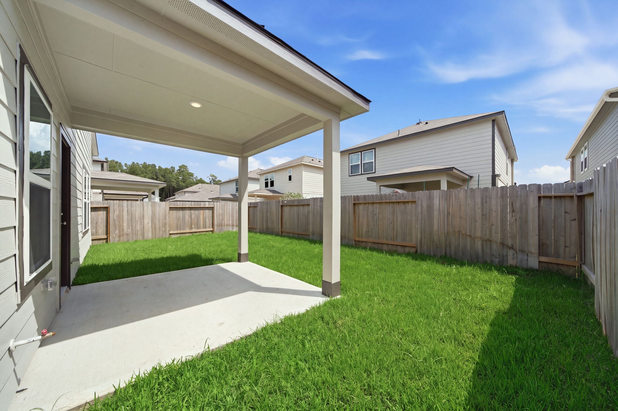 A fenced in yard with a house and a wood fence.