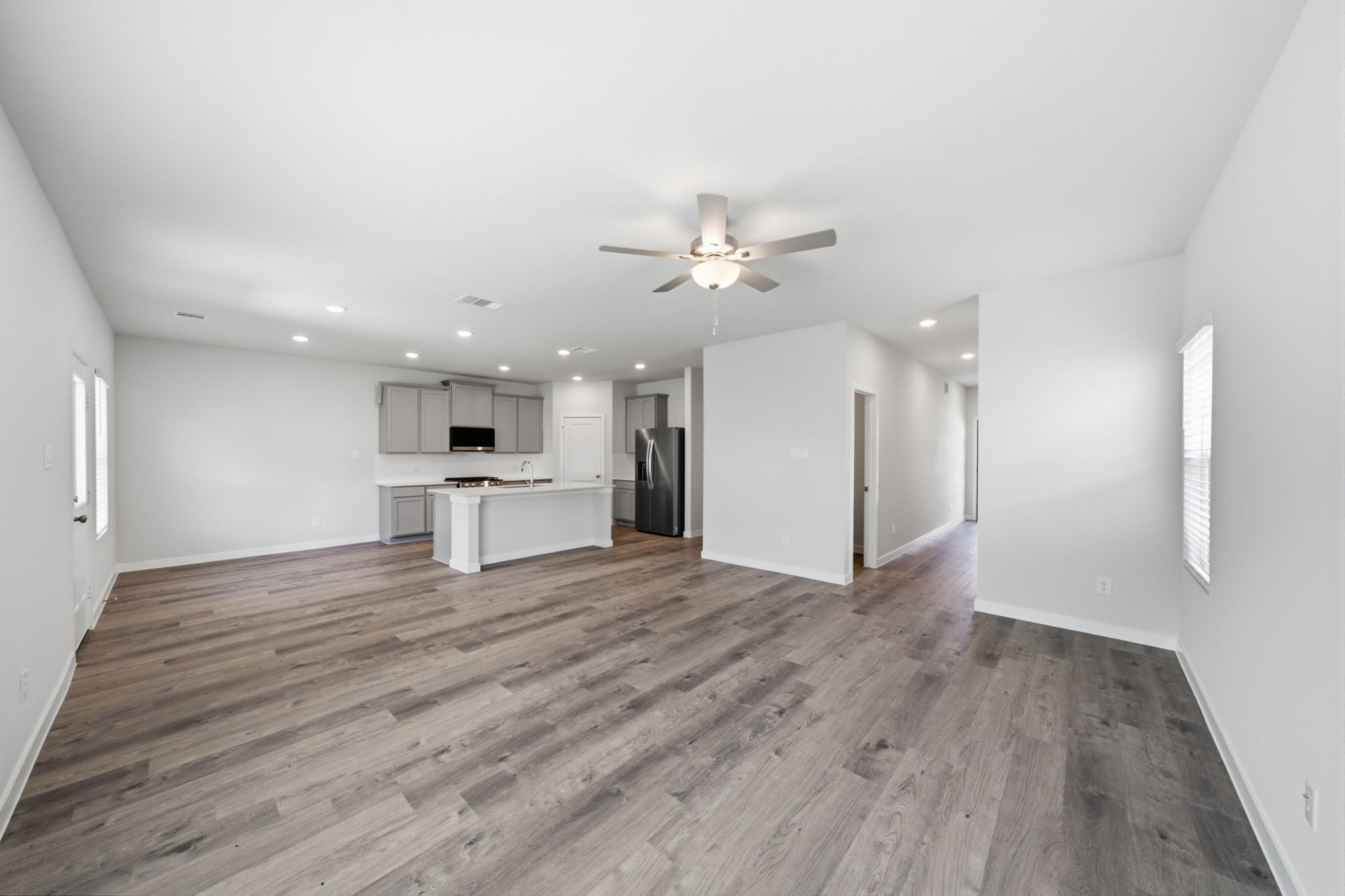 A large empty room with a wood floor and a ceiling fan.