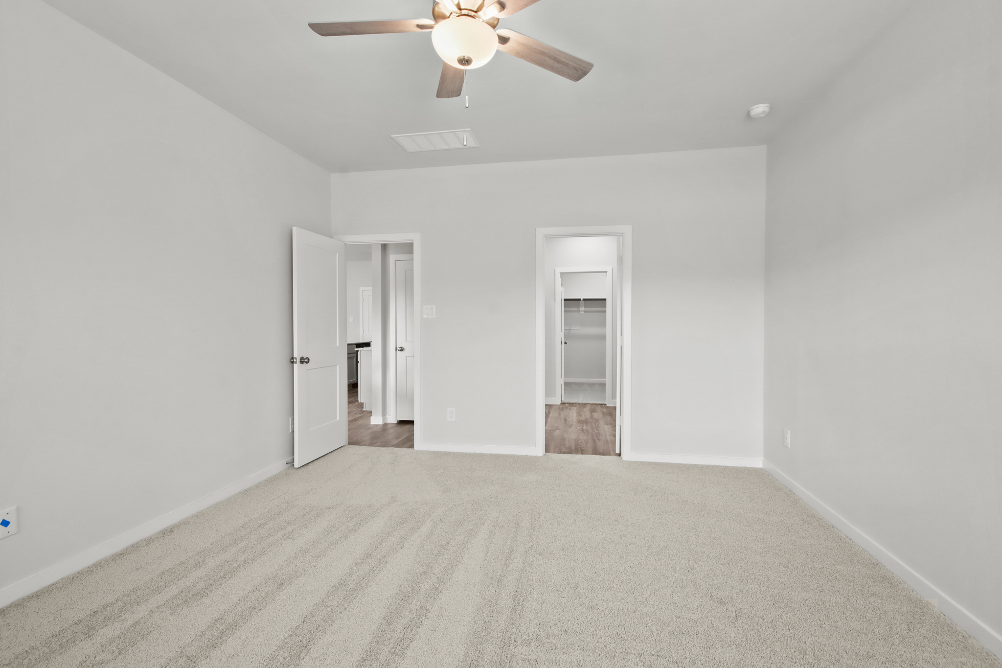 A room with a ceiling fan and a door.