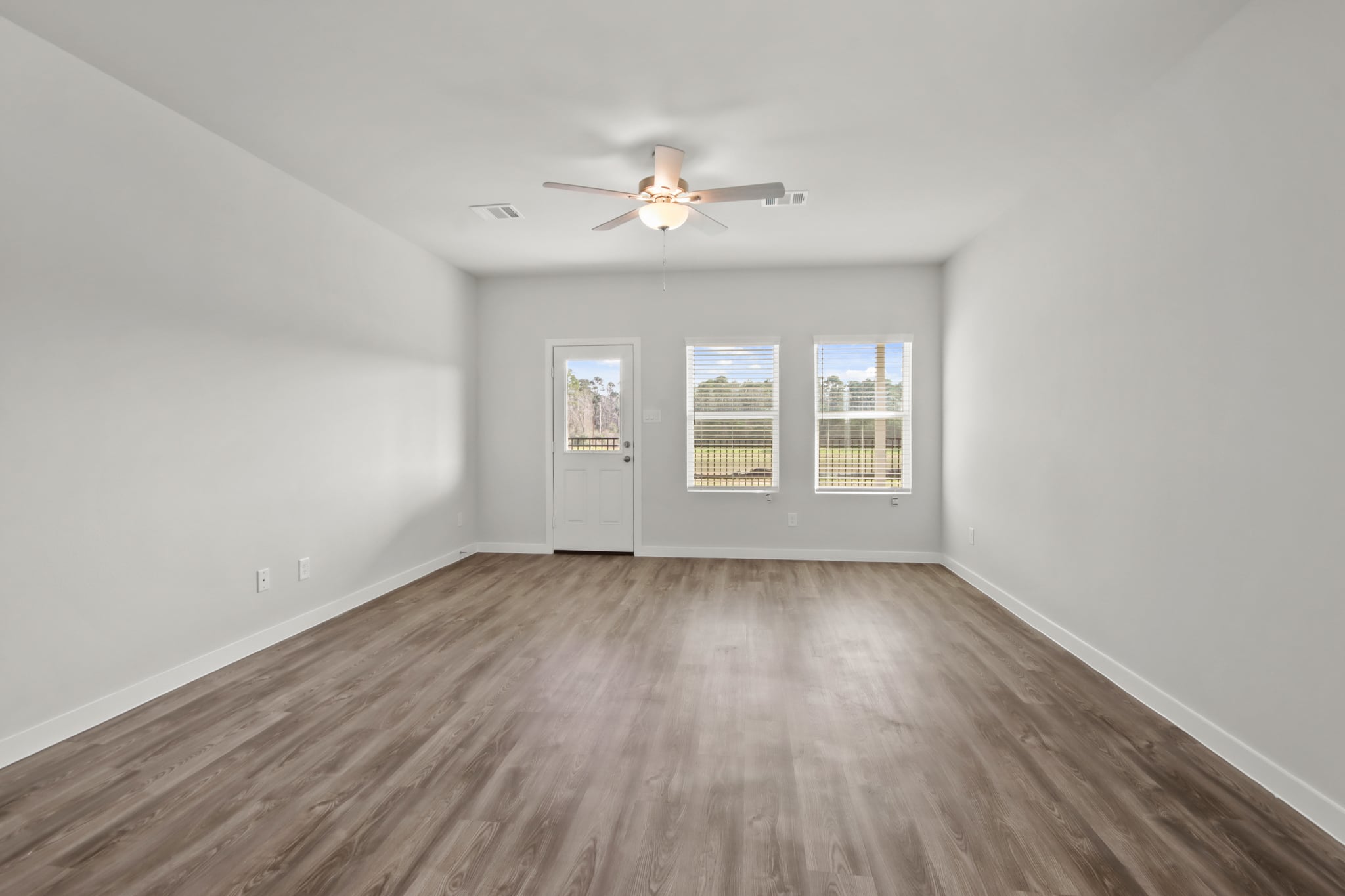 A room with a ceiling fan and a wood floor.