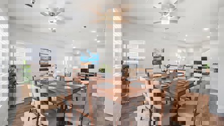 A dining room table with plates and a fan in the background.