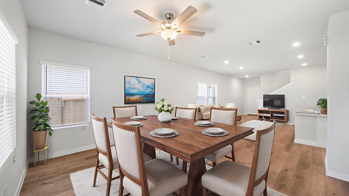 A dining room table with plates and a fan in the background.