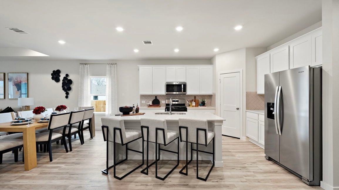 A kitchen with a dining table and chairs.