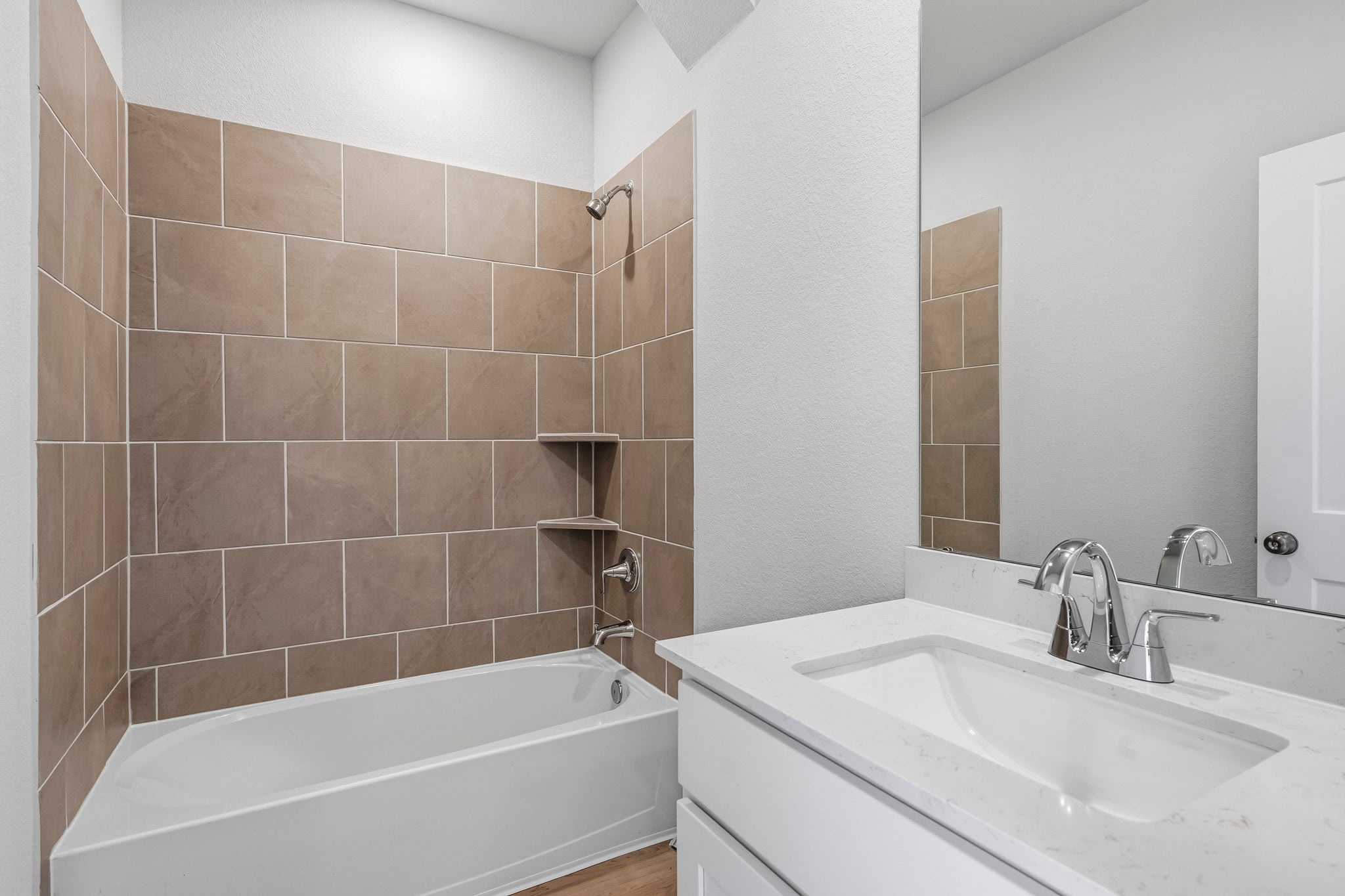 A bathroom with a tub sink and a mirror.