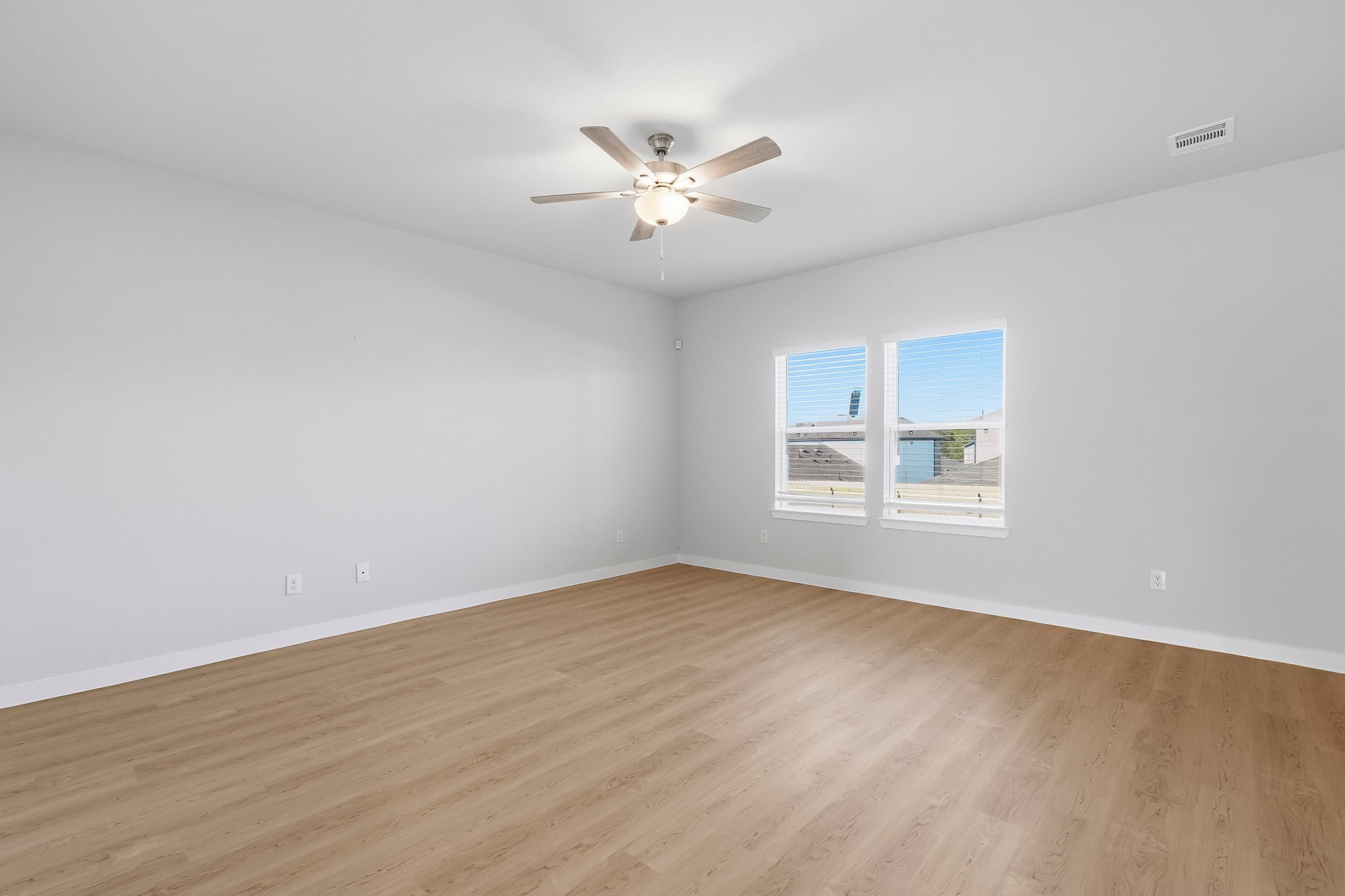 A room with a ceiling fan and a wood floor.