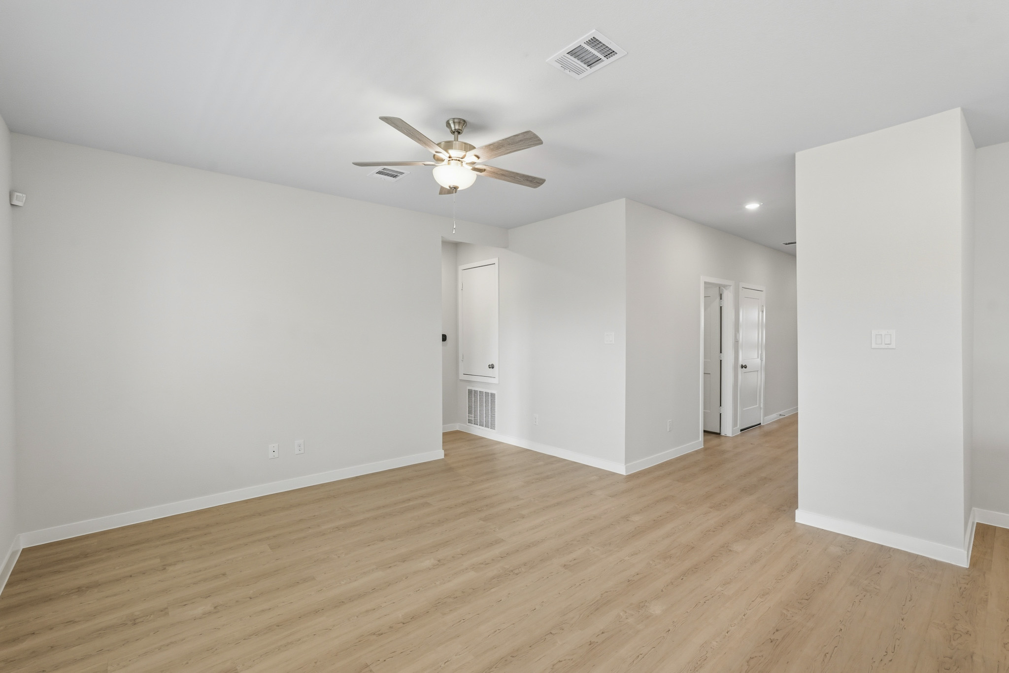 A room with a ceiling fan and a wood floor.
