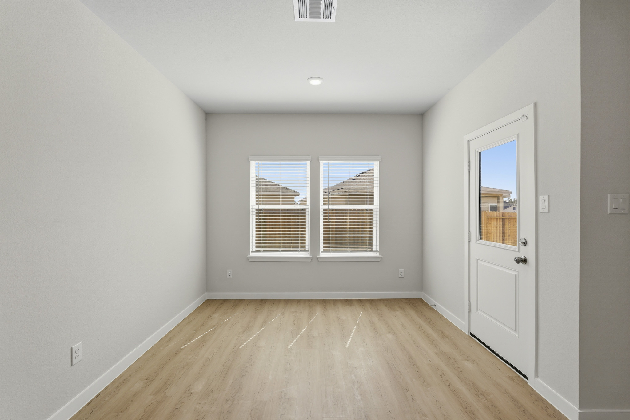 A room with a wood floor and a white door with a window.