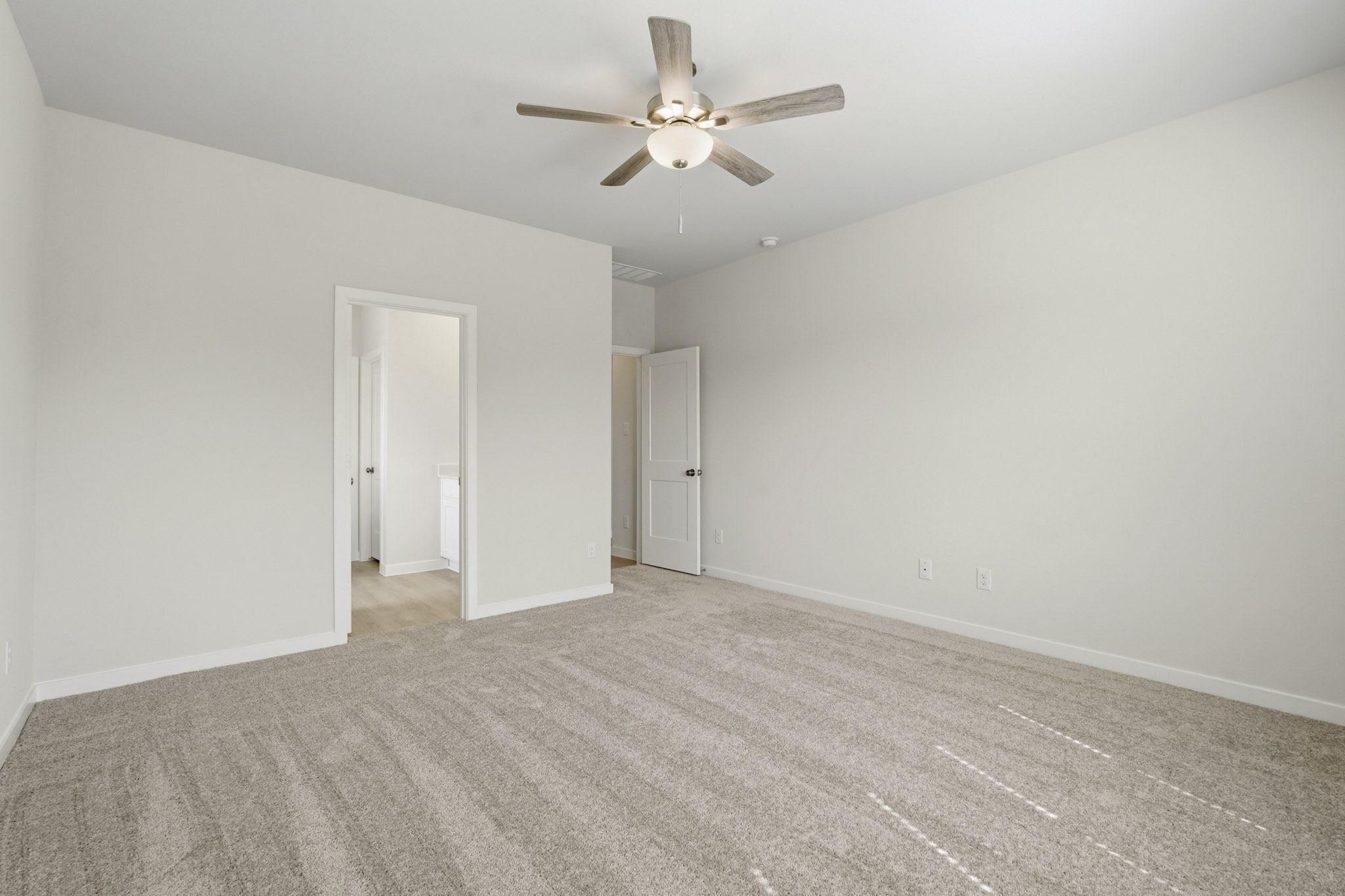 A room with a ceiling fan and a carpet.