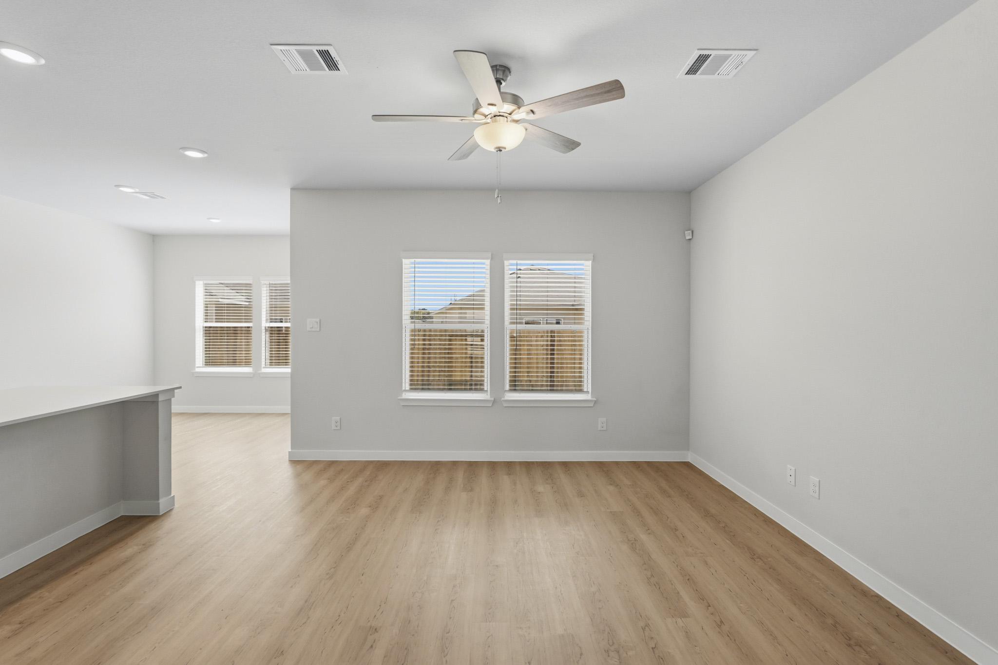 A room with a ceiling fan and a wood floor.
