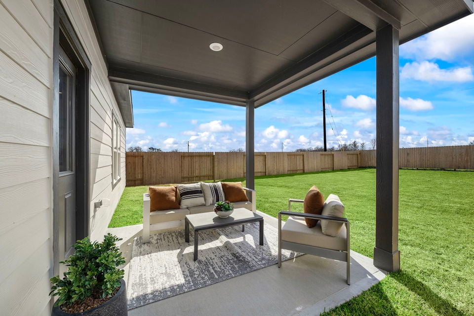 A deck with a table and chairs and a large window with a view of a field and a.