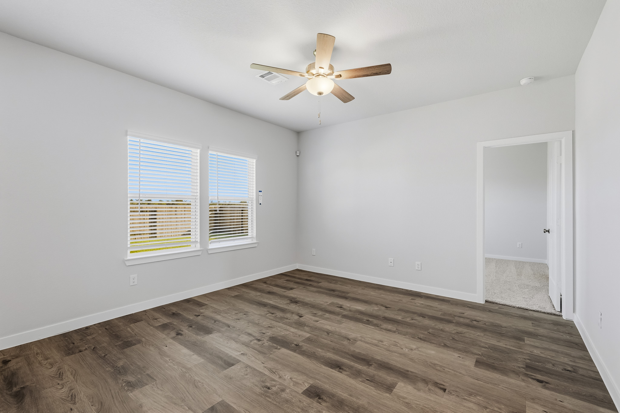A room with a ceiling fan and a wood floor.
