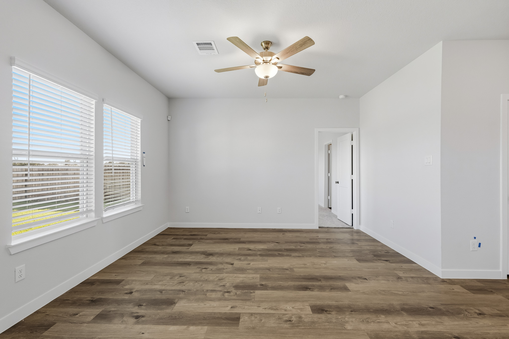 A room with a ceiling fan and a wood floor.