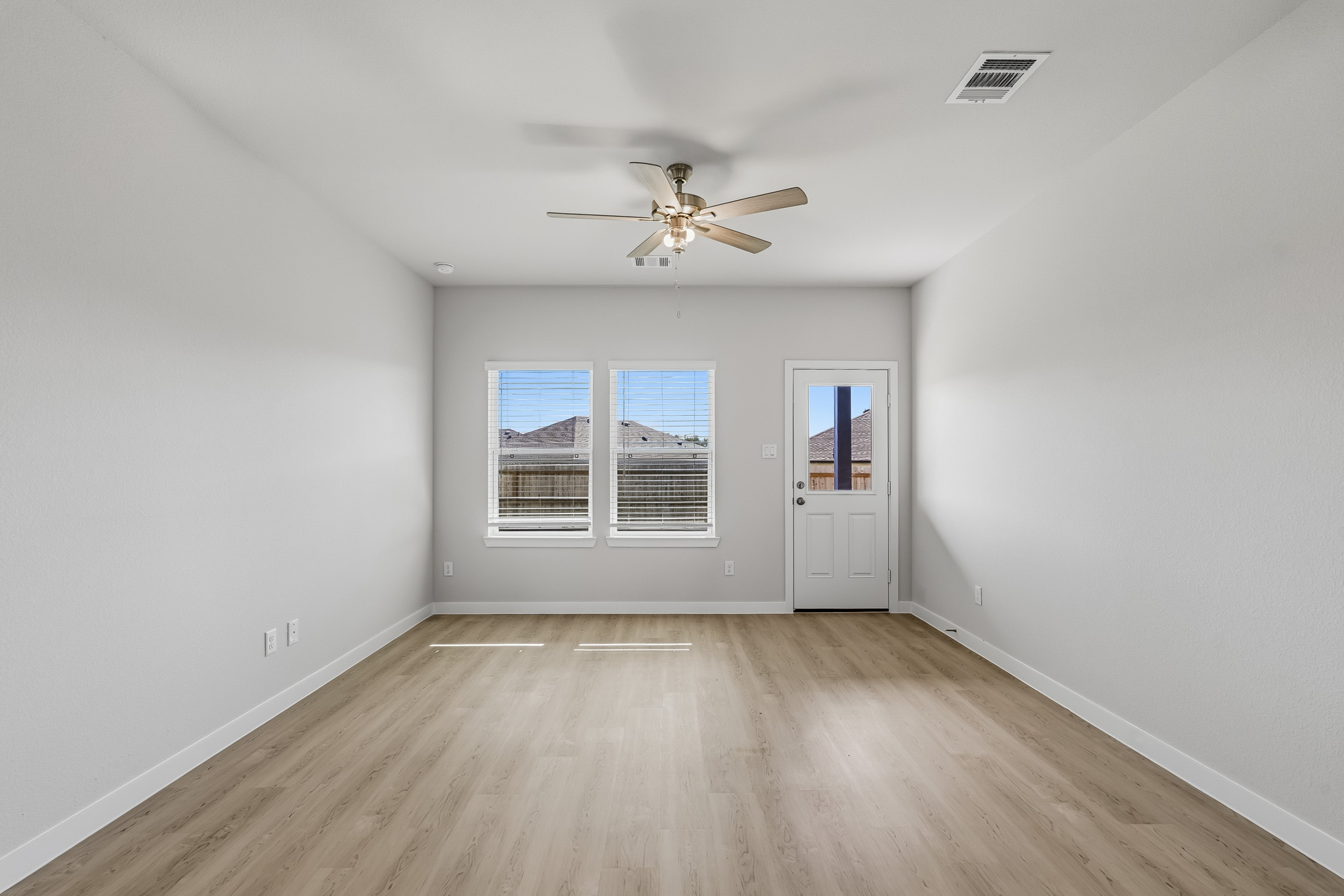 A room with a ceiling fan and a wood floor.