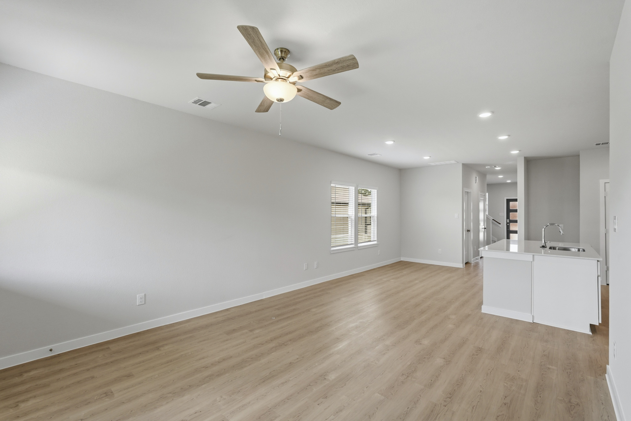 A large empty room with a ceiling fan and a wood floor.