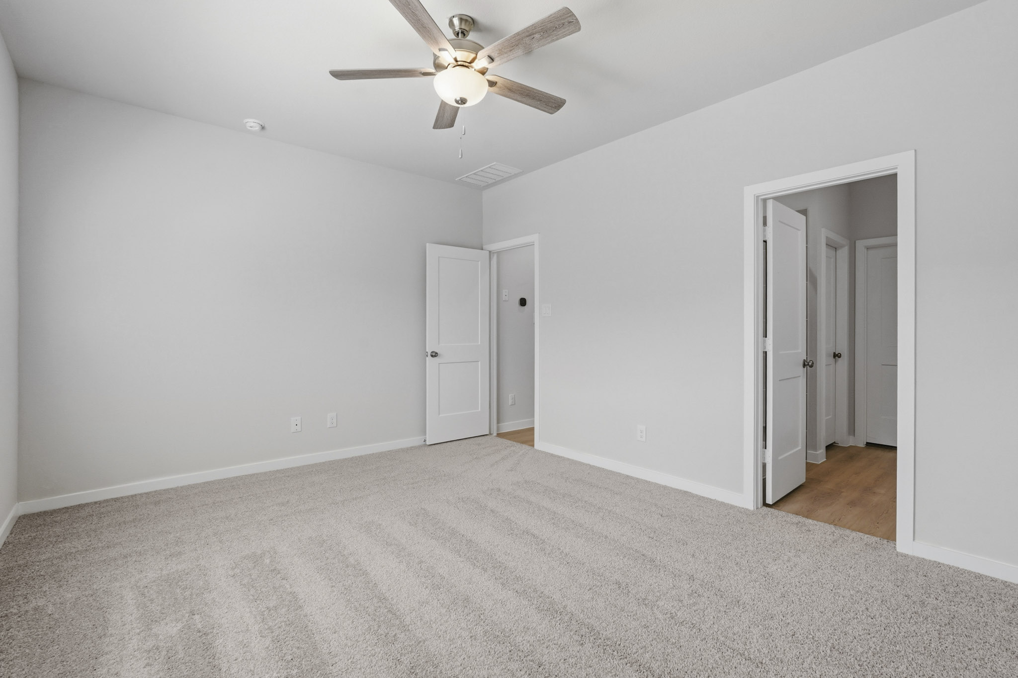 A room with white walls and a ceiling fan.
