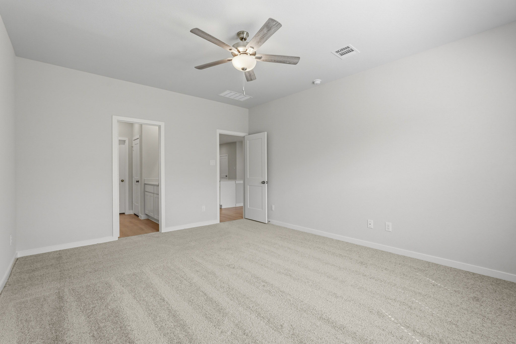 A room with a ceiling fan and a carpet.