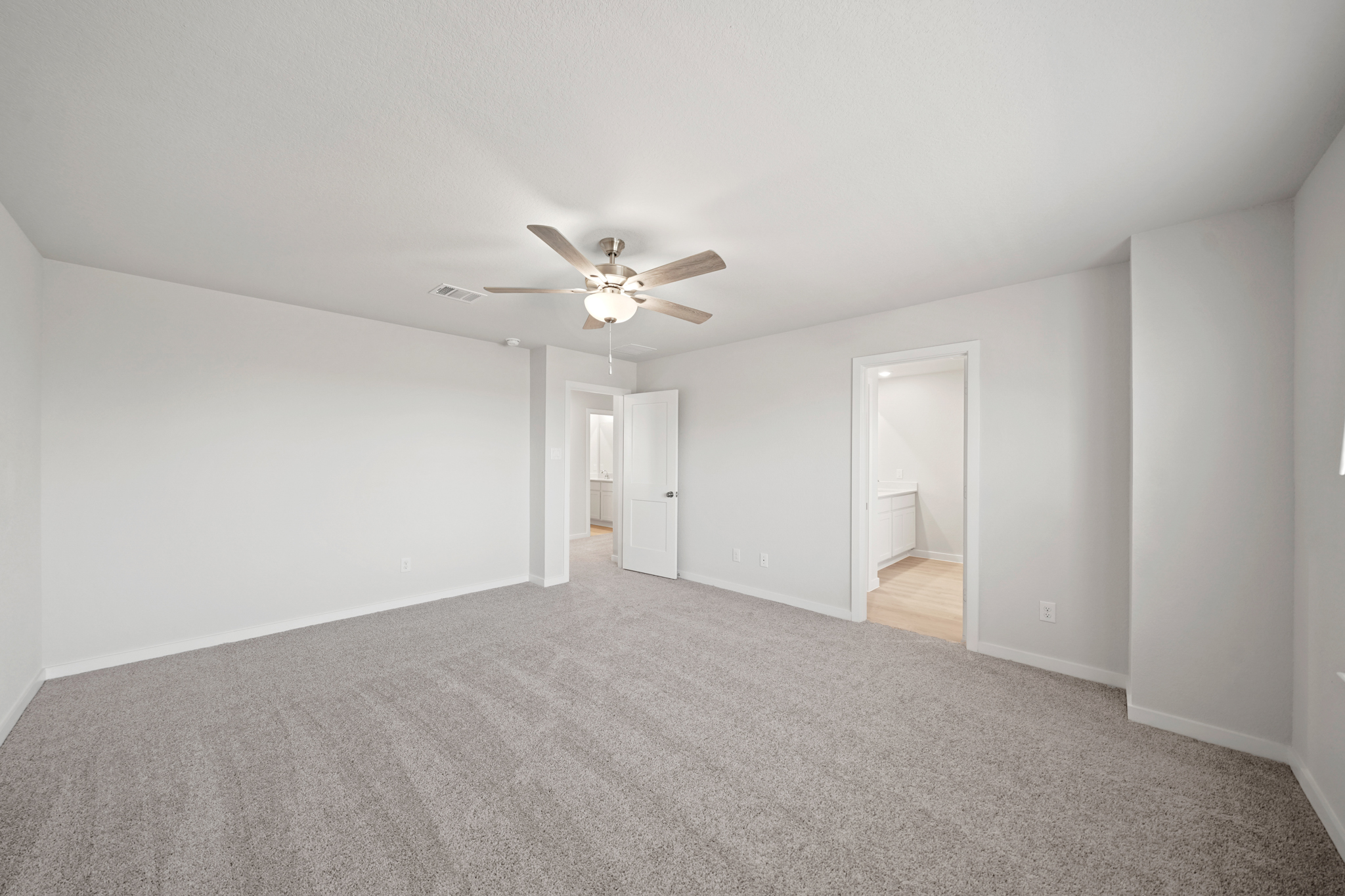 A room with a ceiling fan and a carpet.