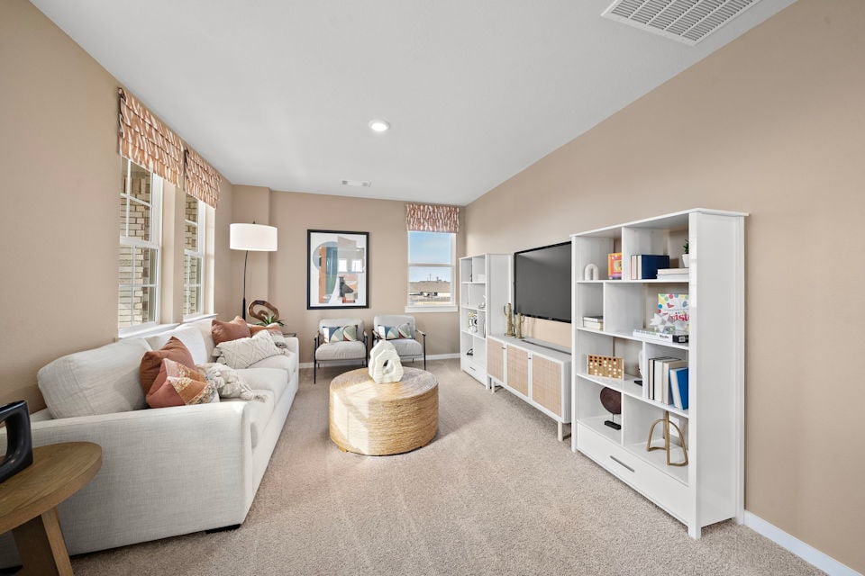 A living room with a white couch and a white bookcase.