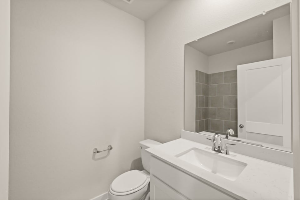 A bathroom with a sink toilet and mirror.