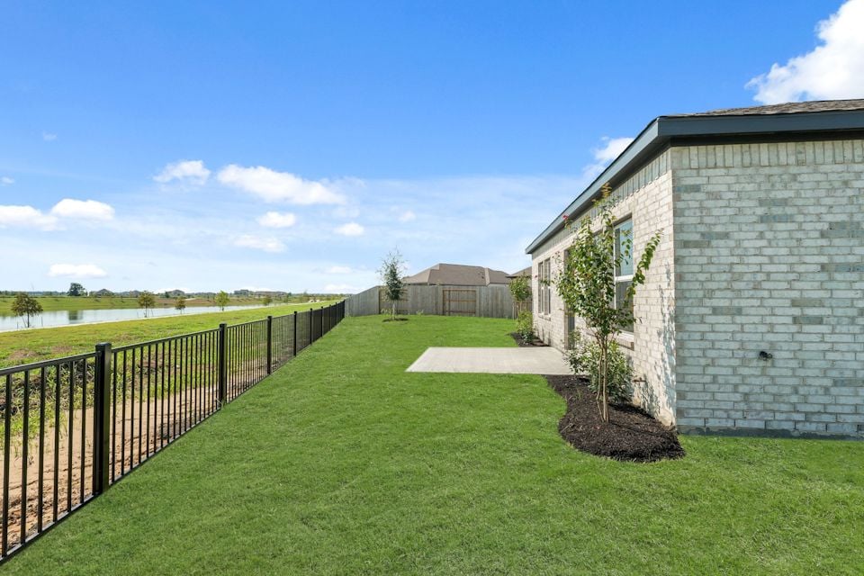 A fenced in yard with a brick building and a tree.