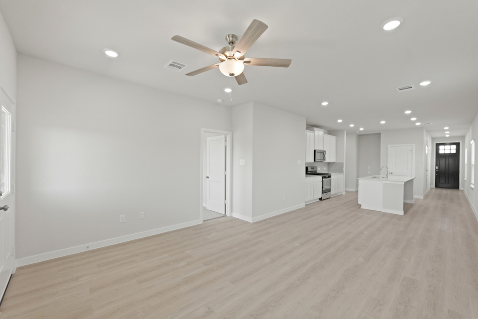 A large empty room with a ceiling fan and a wood floor.