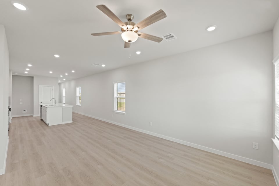 A room with a ceiling fan and wood floors.