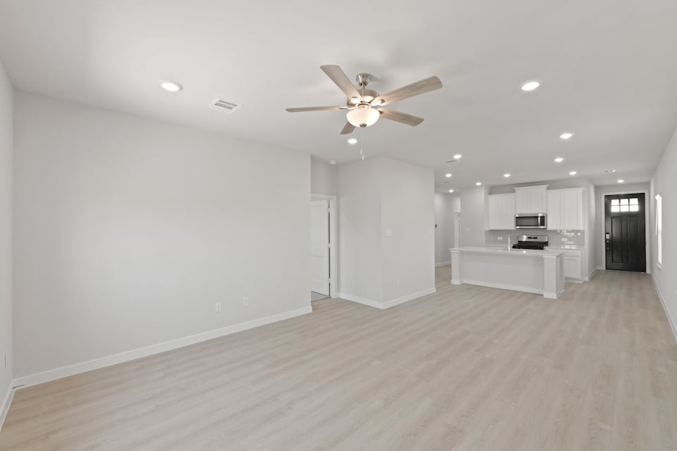 A large empty room with a ceiling fan and a wood floor.