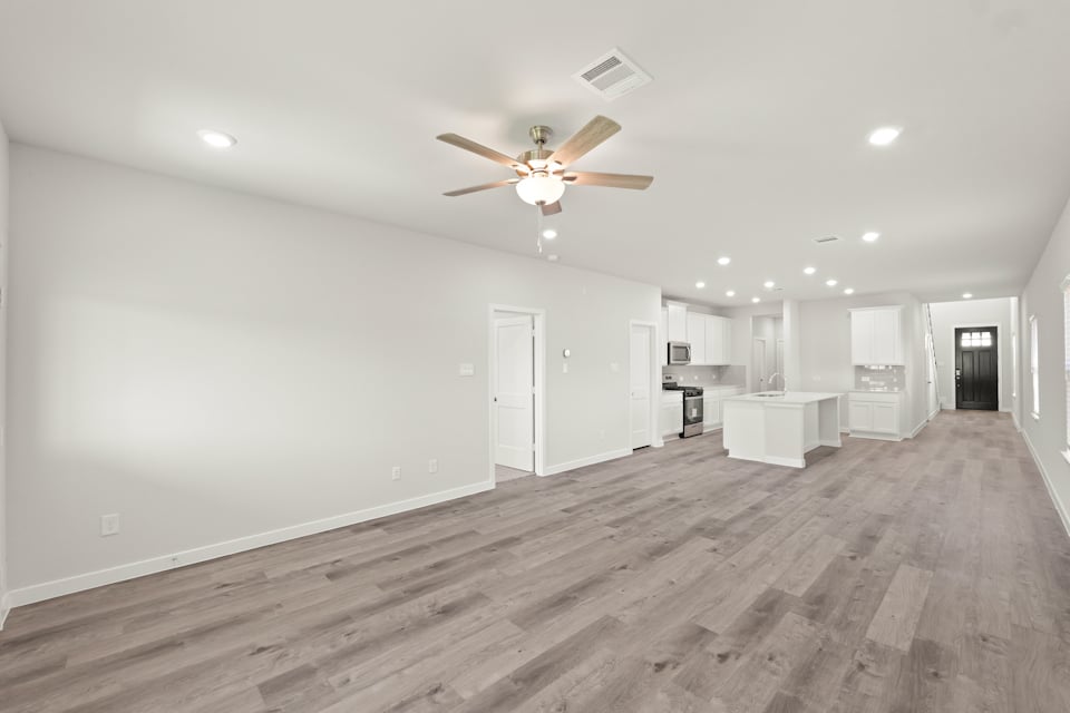 A large empty room with a ceiling fan and a wood floor.