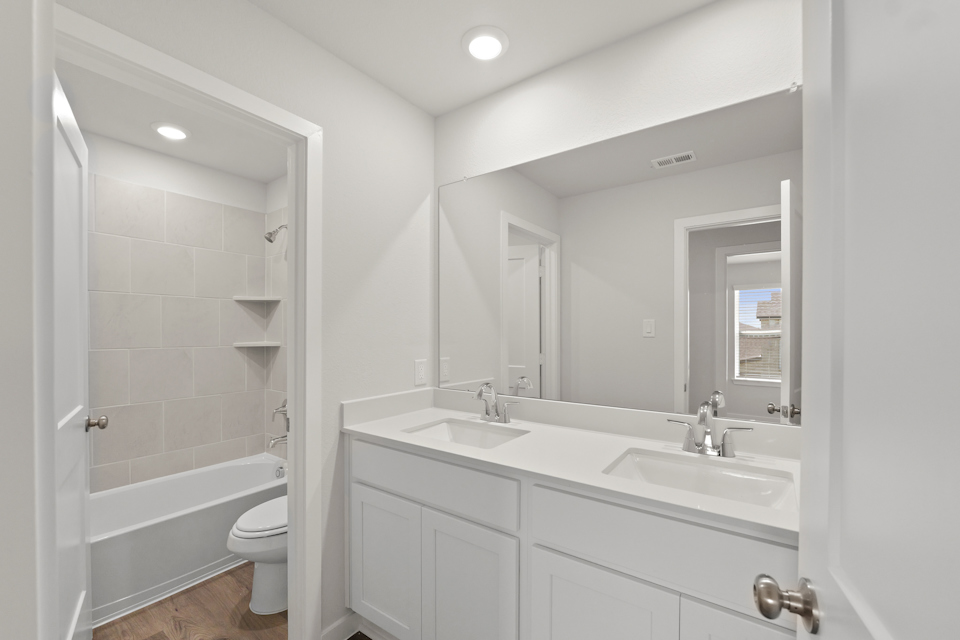 A bathroom with a sink toilet and mirror.