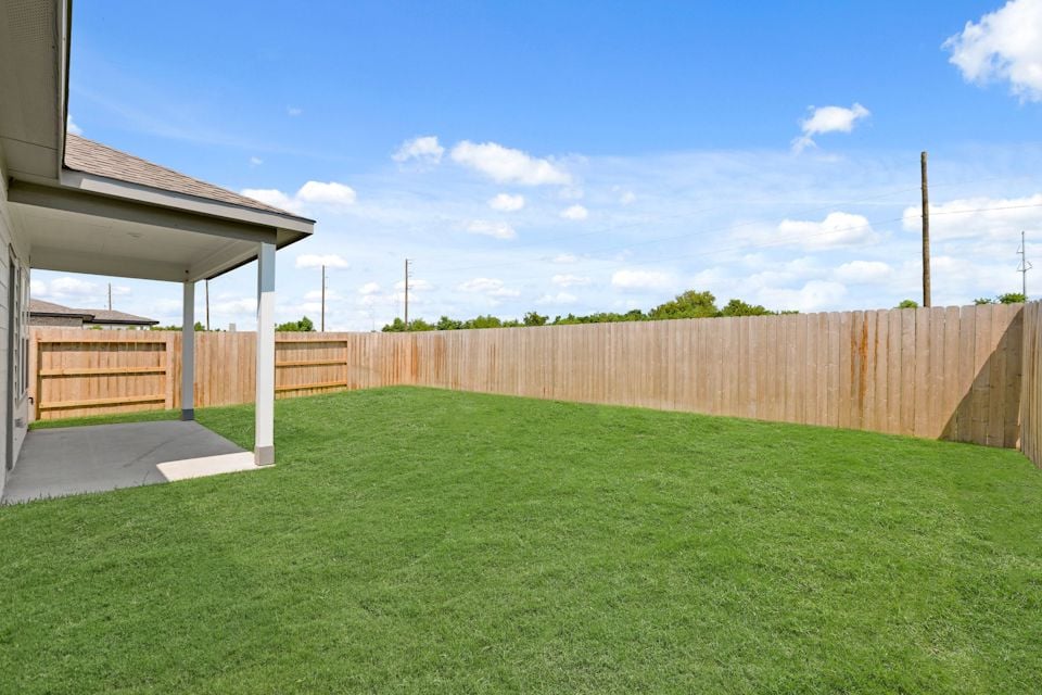 A fenced in yard with a house and a wood fence.