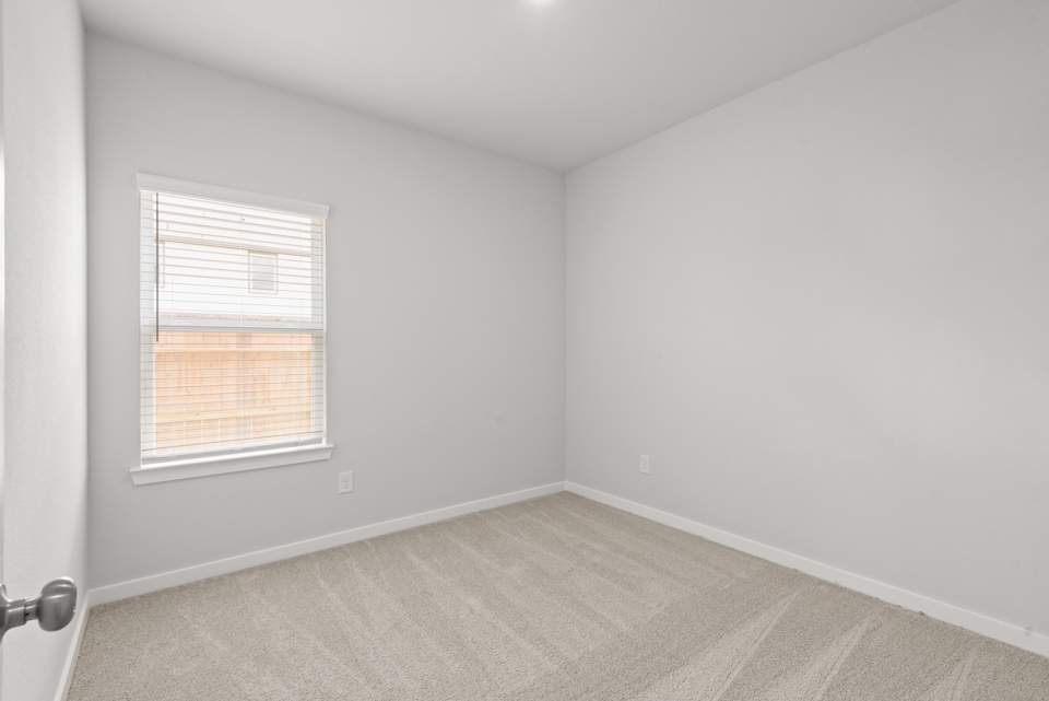 A room with a window and a rug.