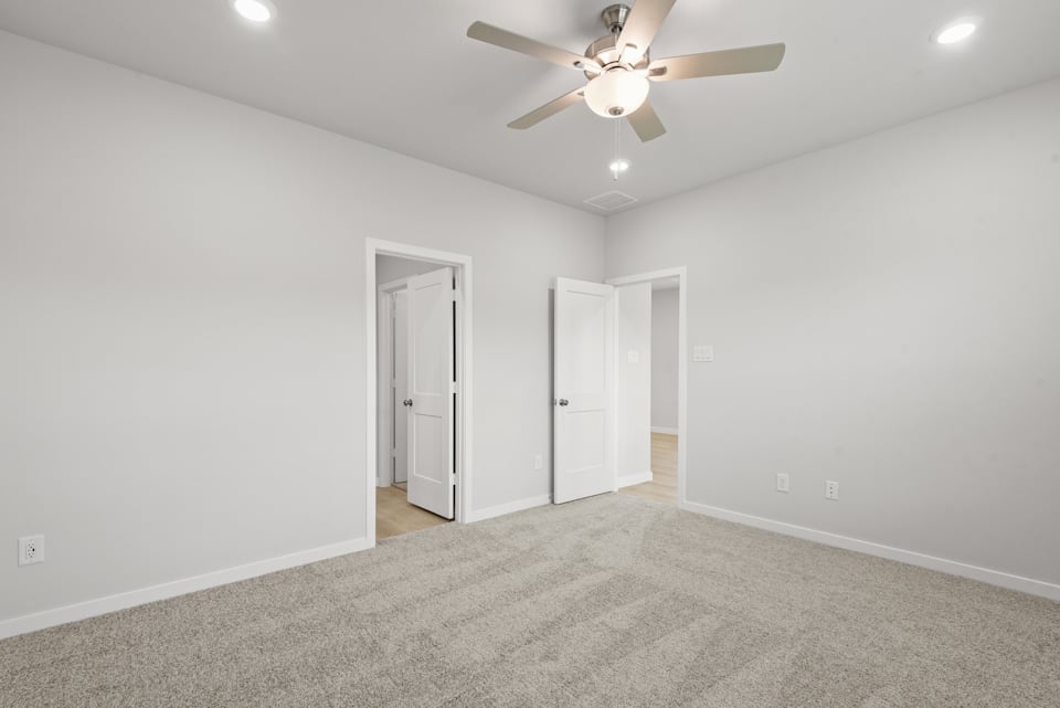 A room with a ceiling fan and white walls.