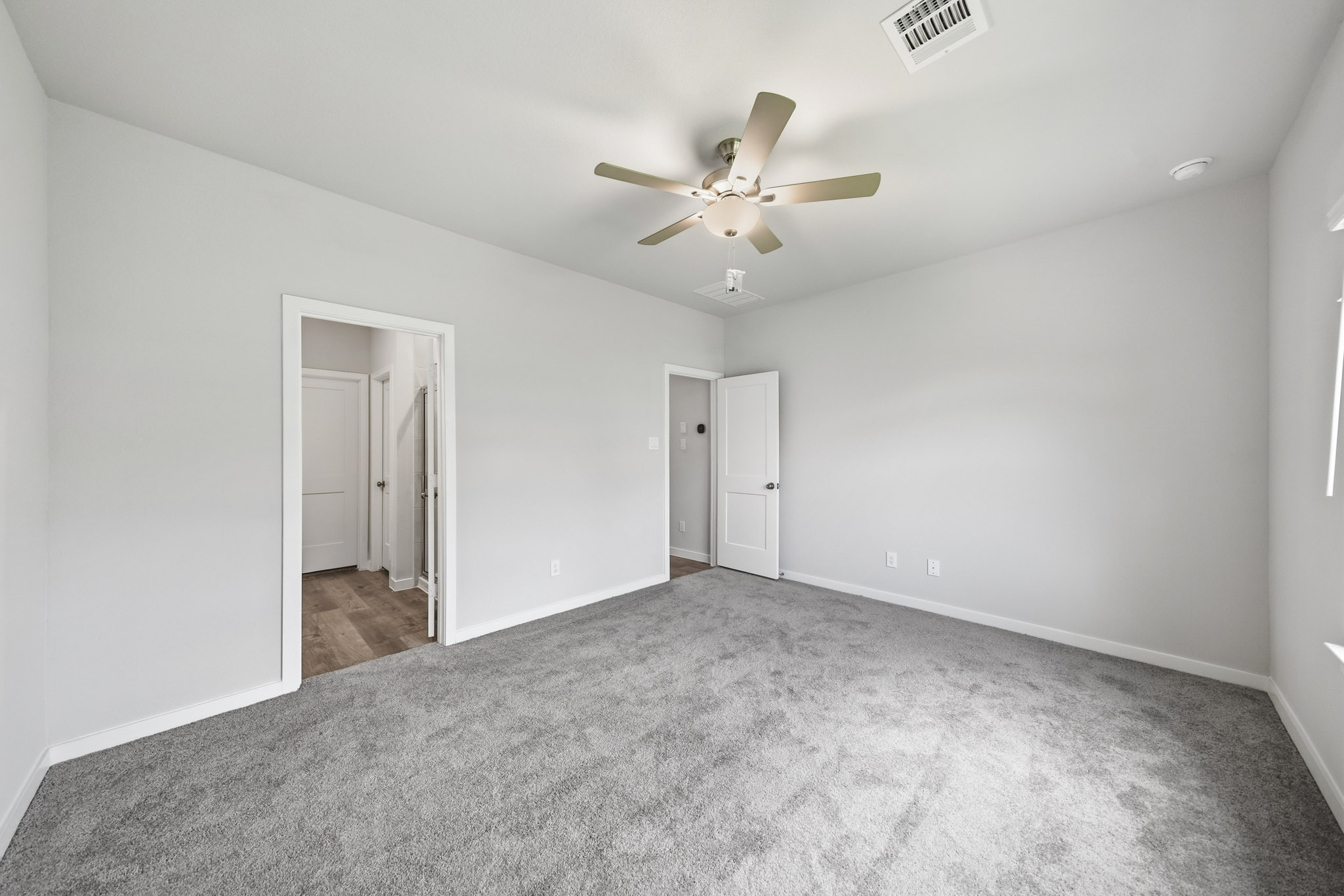 A room with a ceiling fan and a door.
