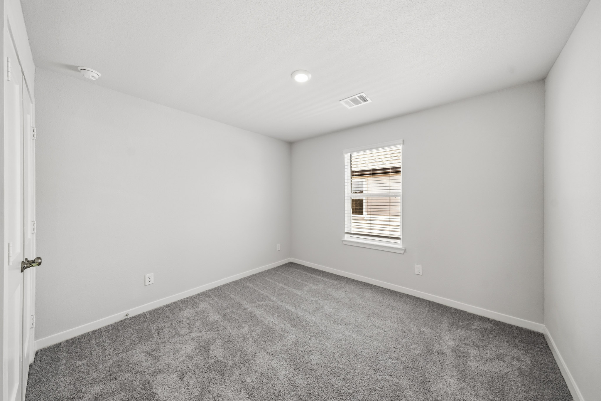 A room with a carpet and a door.