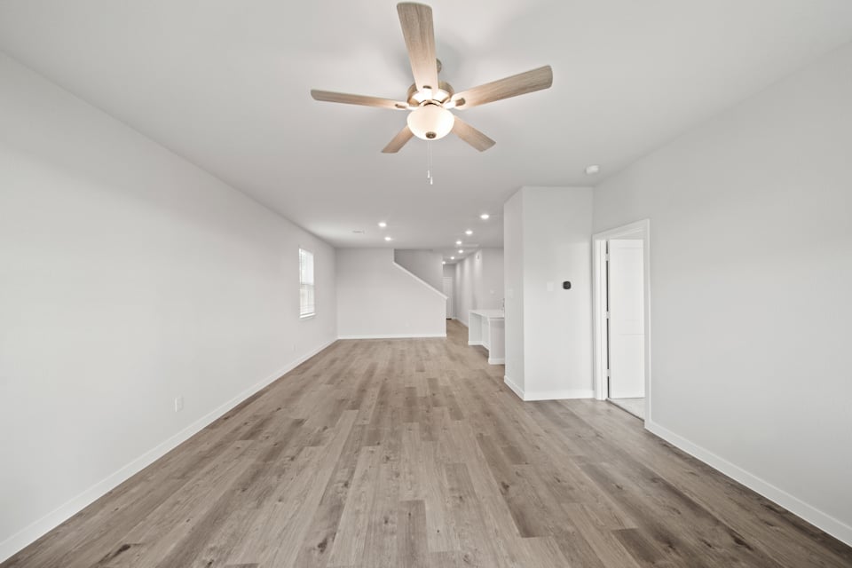 A room with a ceiling fan and wood floor.