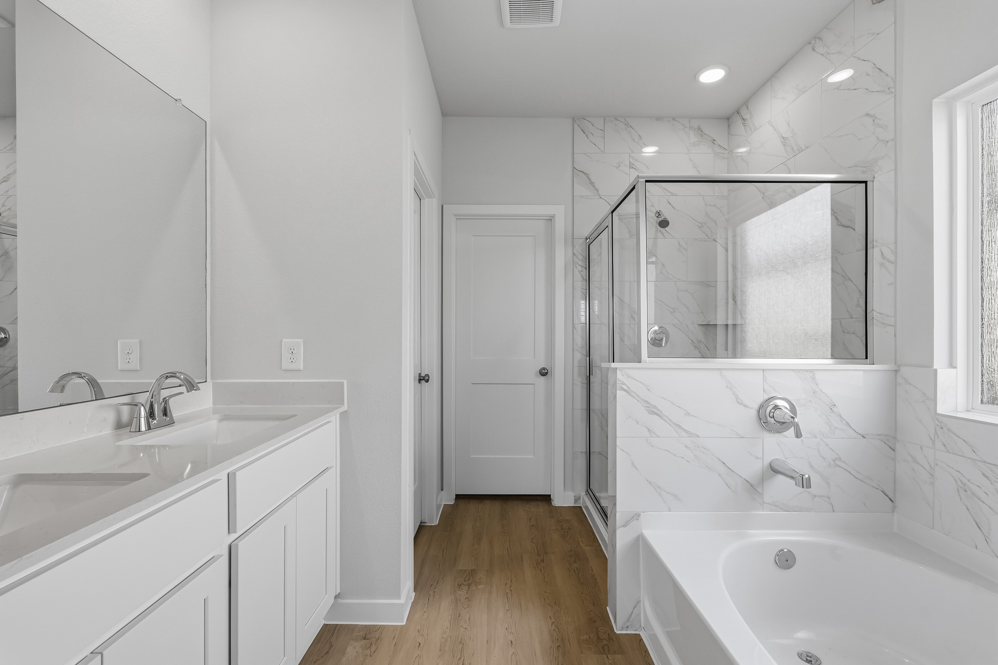 A bathroom with a tub sink and mirror.