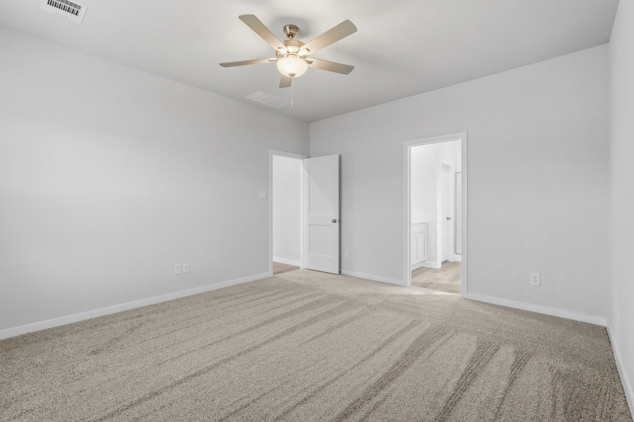 A room with a ceiling fan and a carpet.