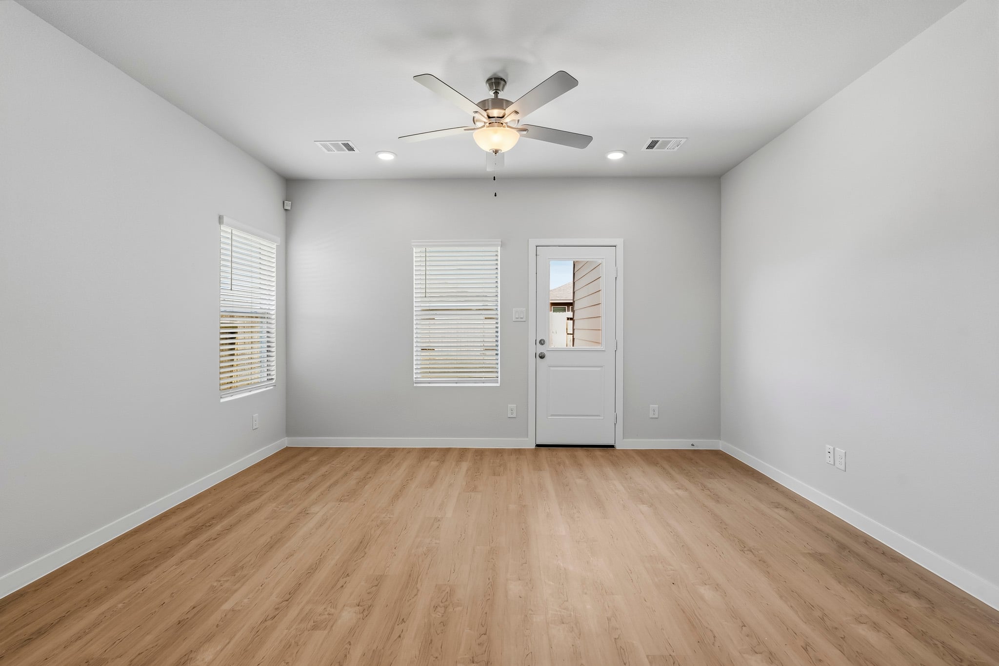 A room with a ceiling fan and a wood floor.
