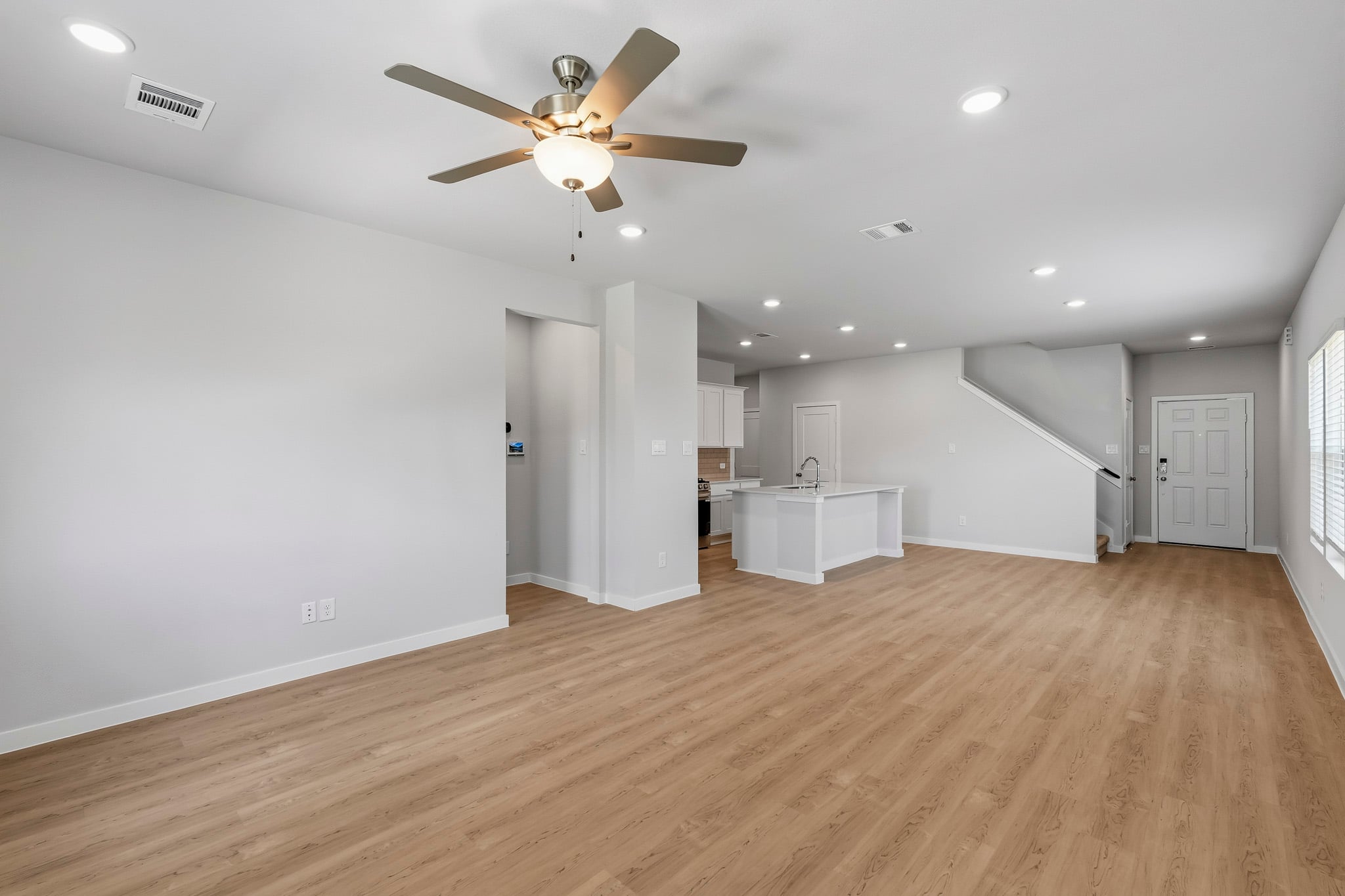 A room with a ceiling fan and a wood floor.