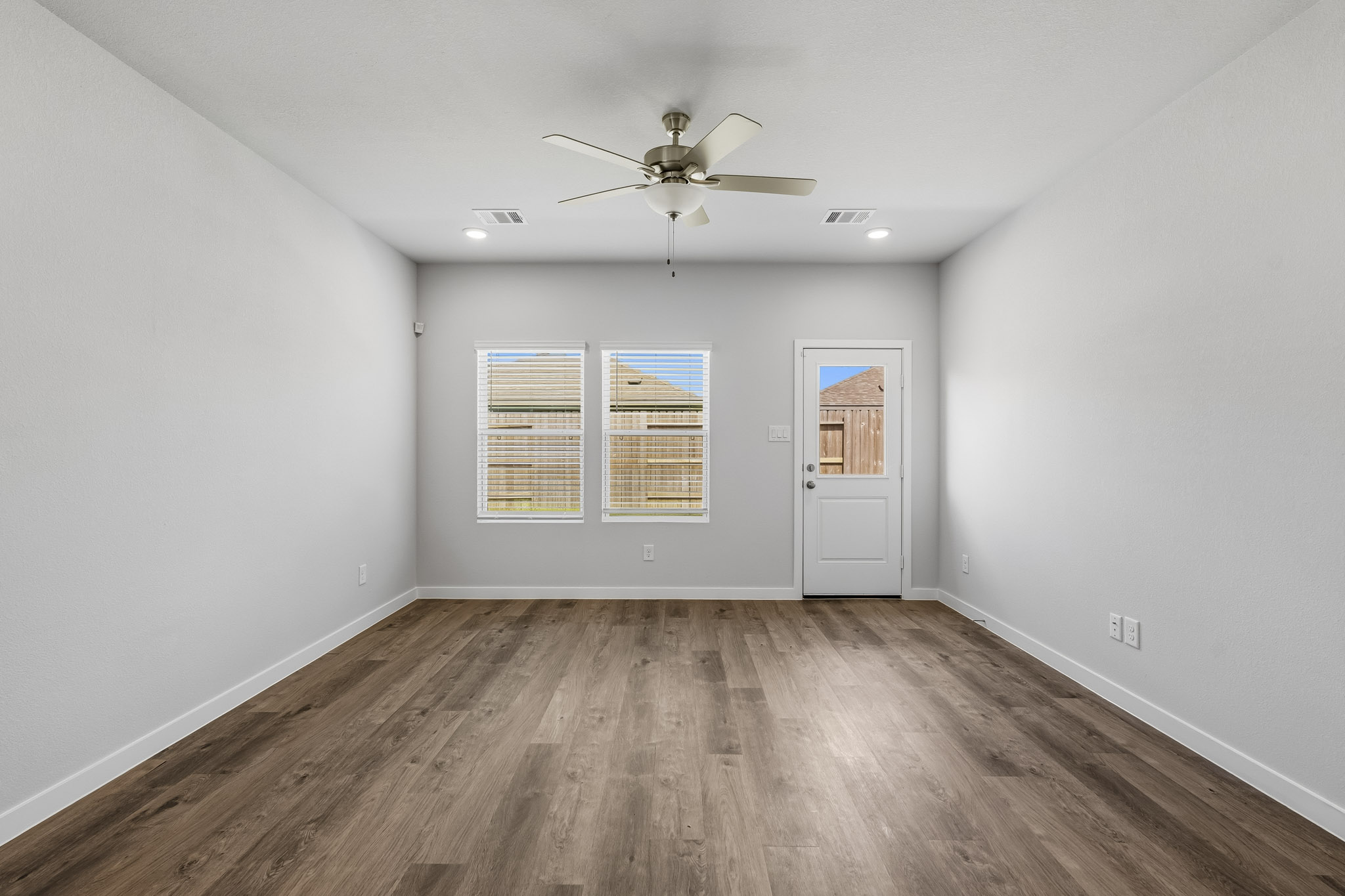A room with a wood floor and a ceiling fan.
