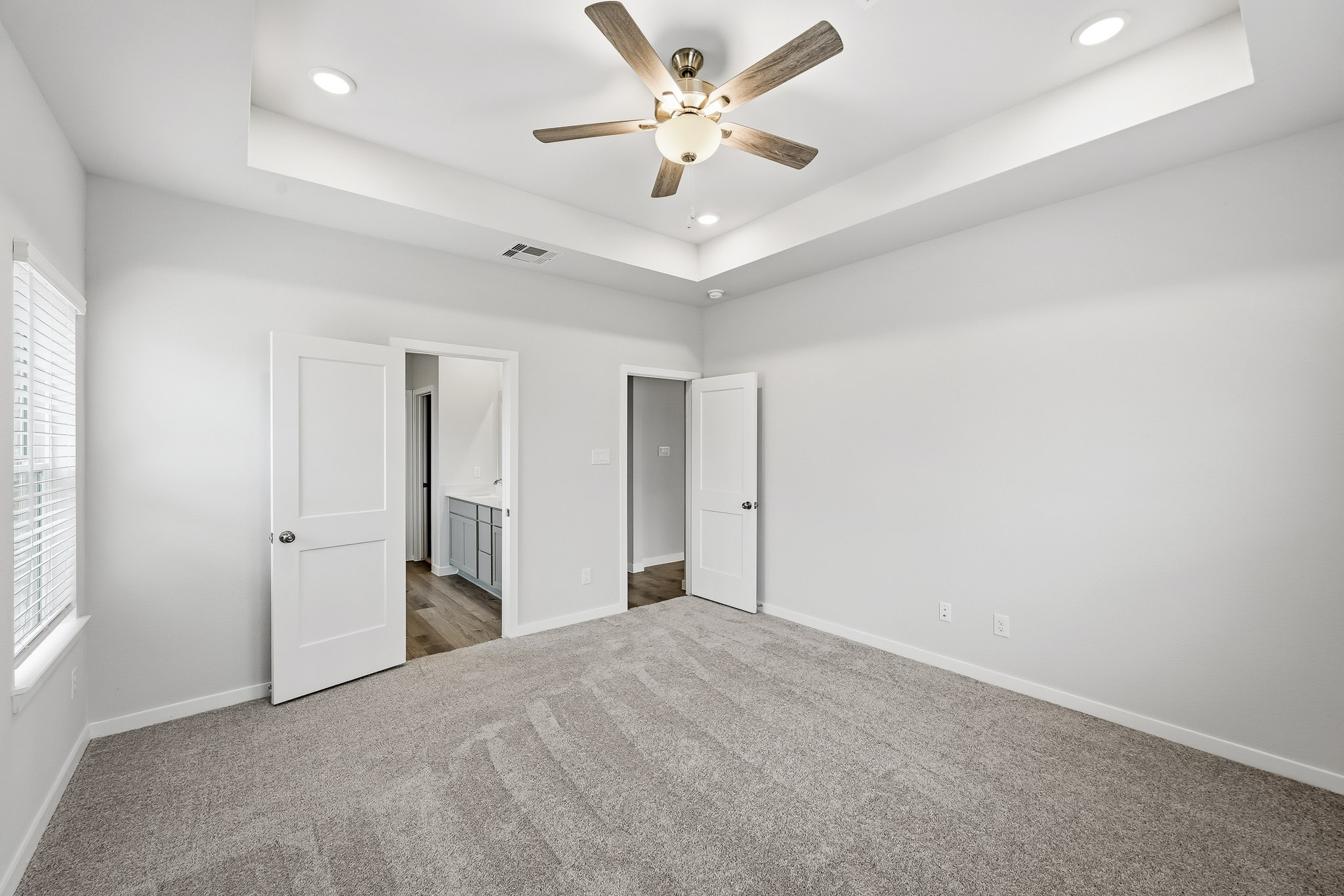 A room with a ceiling fan and white doors.