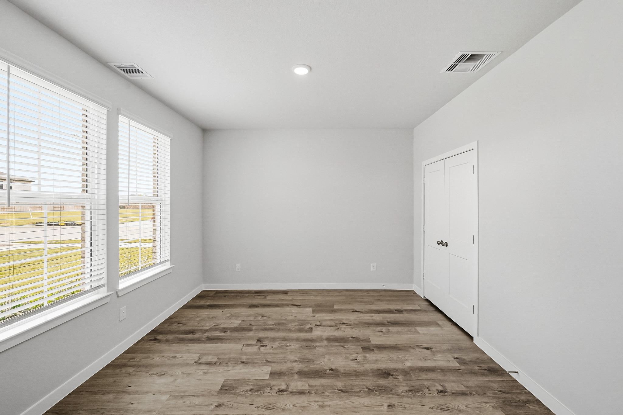 A room with a wood floor and windows.
