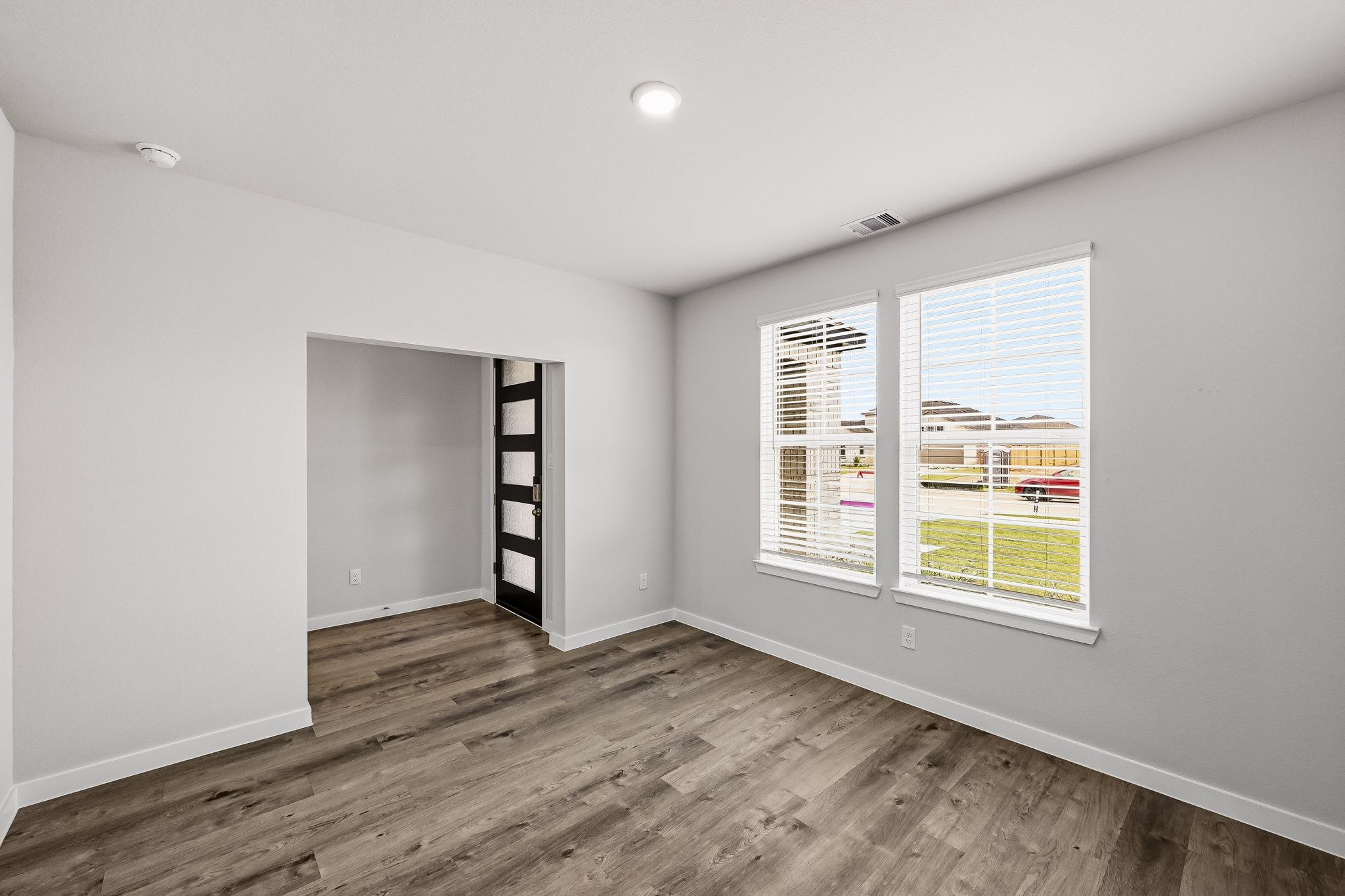 A room with a wood floor and a window with blinds.